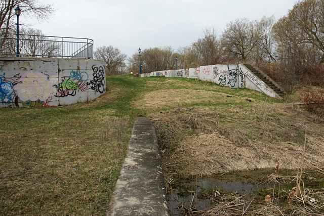 The highest lock on the canal has been filled in. A recreational trail crosses the top of the lock structure and continues at the left of the picture where the guardrail is.