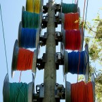 Colourful spools of cable await deployment along a line of utility poles